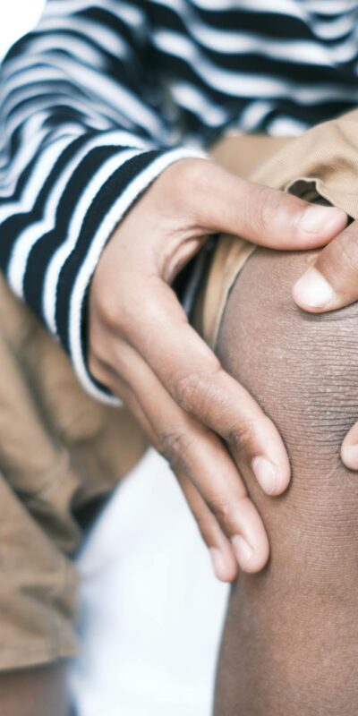 Person in Black and White Stripe Shirt Pinching Skin on Knee