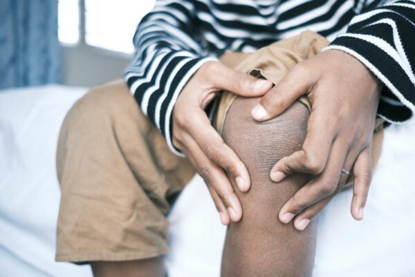 Person in Black and White Stripe Shirt Pinching Skin on Knee